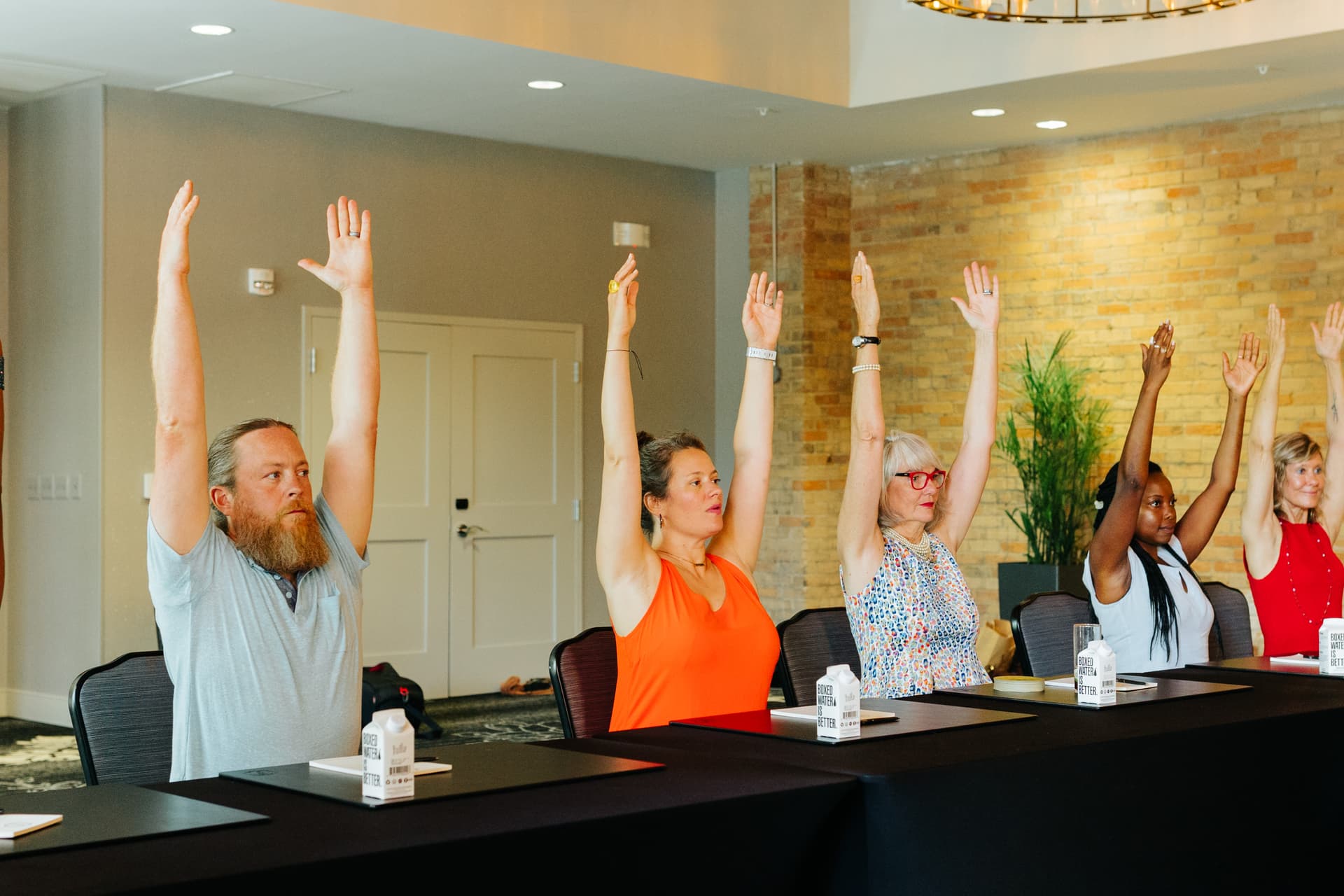 Group of adults sitting at conference table doing yoga stretch break Group of adults sitting at conference table doing yoga stretch break