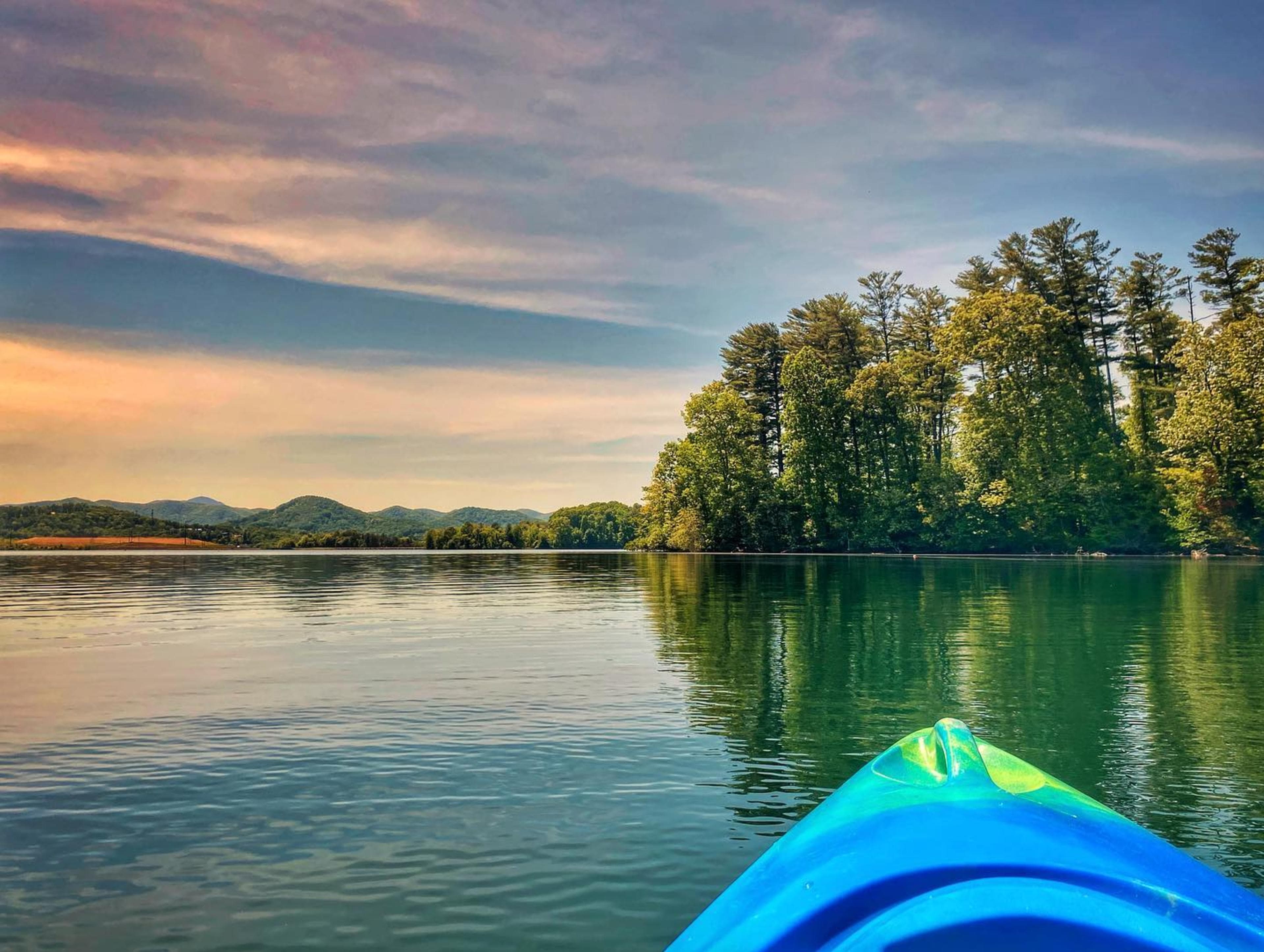 a kayak floats on a lake looking at a shore at sunset a kayak floats on a lake looking at a shore at sunset