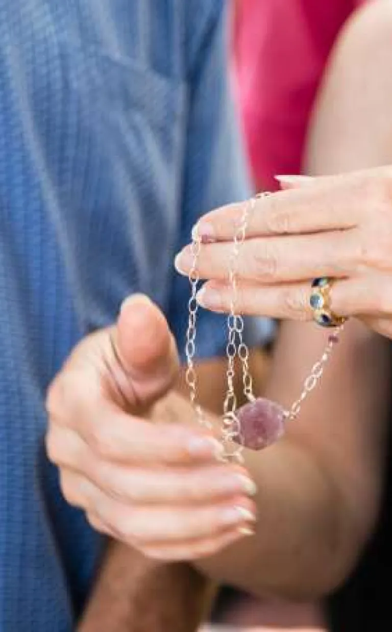 Asheville Artists Create Jewelry You’ll Always Treasure a person holds a necklace with a large purple stone in their hand in Asheville