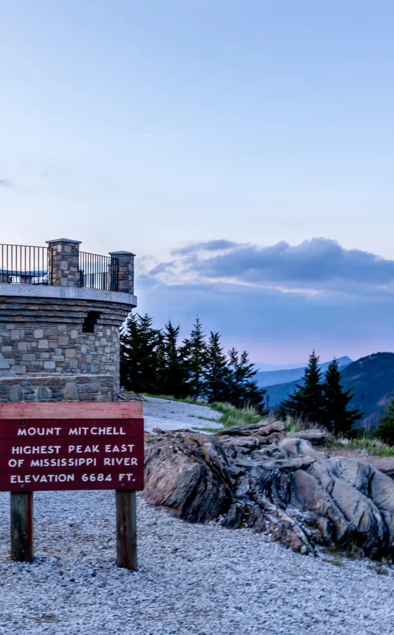 Home of the Highest, Oldest Peaks a sign read "Mt. Mitchell" at sunset, overlooking beautiful mountains