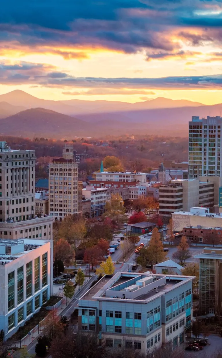 Budget-Friendly Tips for a Midweek Trip to Asheville The sun rises behind downtown Asheville